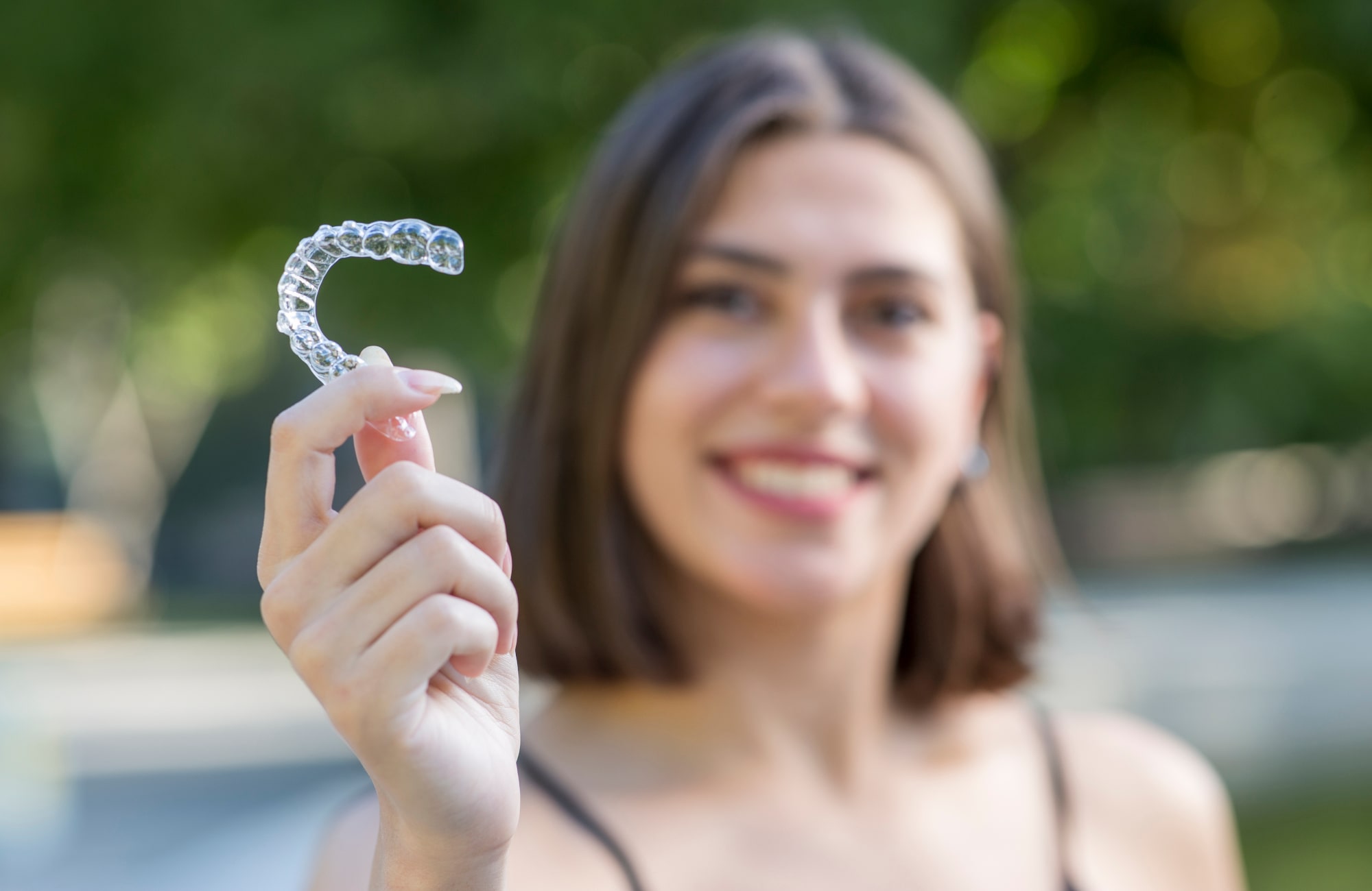 A customer from an Invisalign dentist in Kalamazoo holds her aligner.