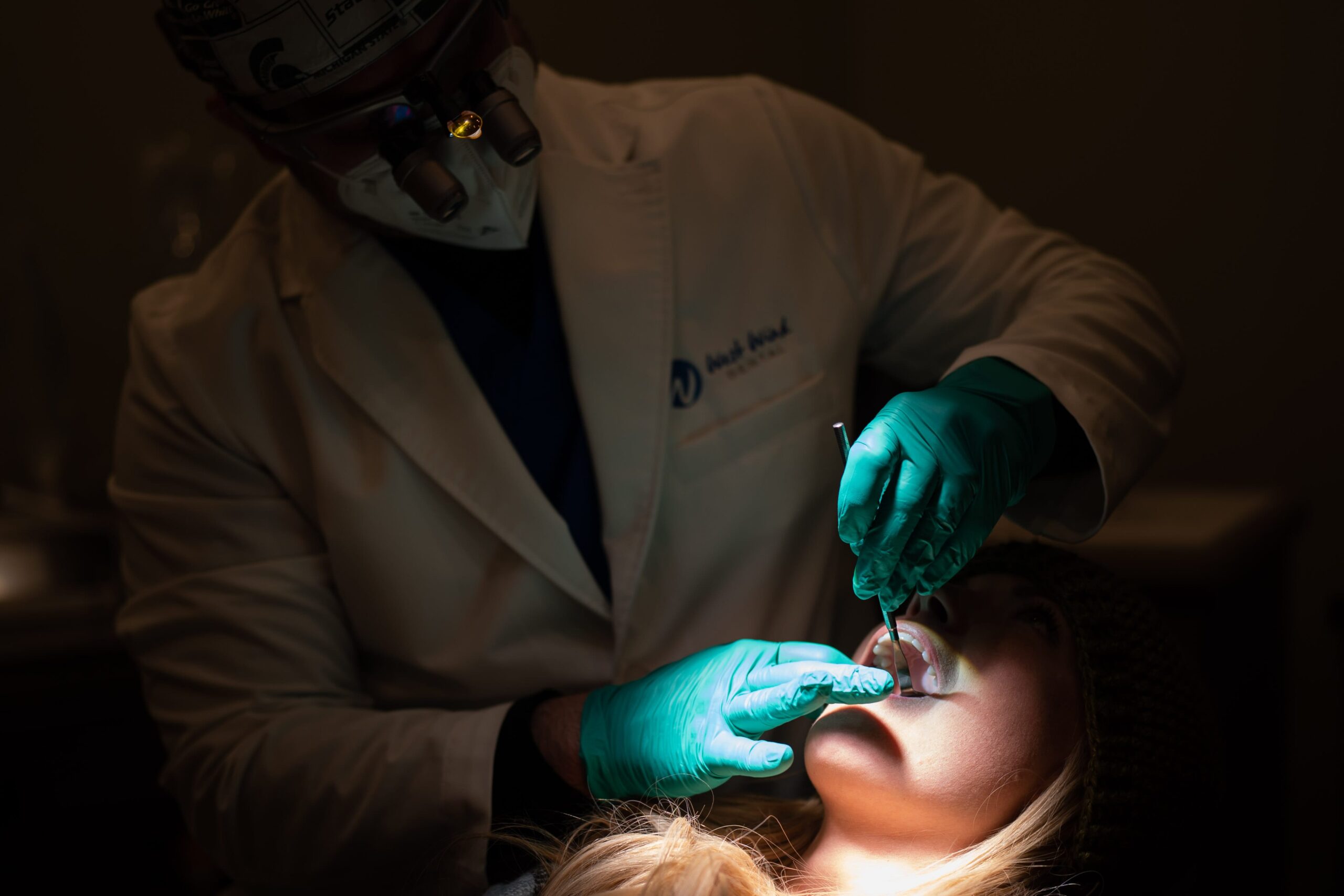 A dentist in a dark room inspecting a patient for bone loss in their teeth.