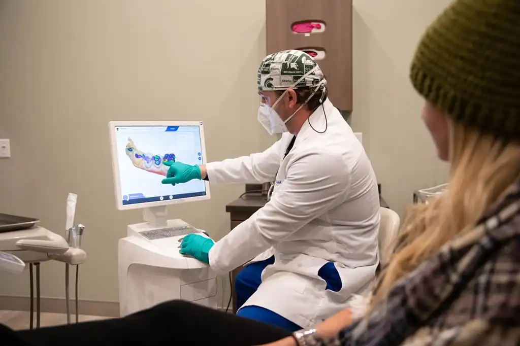 A dentist at West Wind Dental shows his patient what a cavity looks like in their teeth.